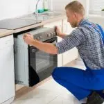 Un instalator care face montaj aragaz pret redus într-o bucătărie.